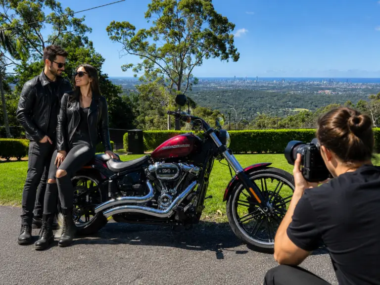 Couple posing with a Harley-Davidson Breakout during a professional photoshoot overlooking the Gold Coast skyline